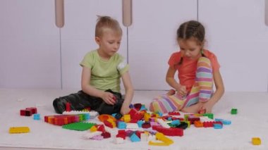 Children are sitting on carpet and playing with colorful lego building blocks