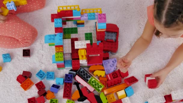 Children play colorful plastic constructor sitting on a carpet in kindergarten — Stock Video