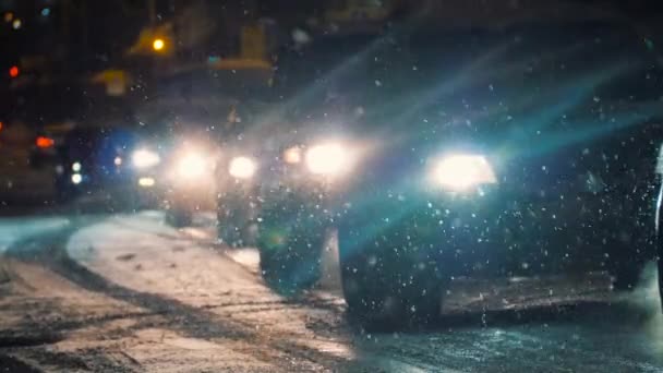 Cars driving through epic snowfall in winter. Night city traffic moving. — Stok video