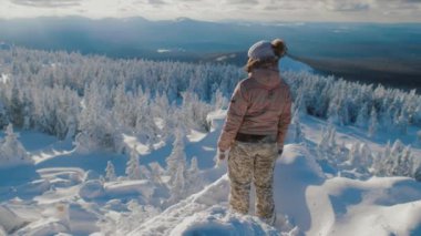 Woman hiker standing on top of snowy mountain, enjoying view