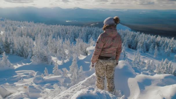 Mujer excursionista de pie en la cima de la montaña nevada, disfrutando de la vista — Vídeos de Stock