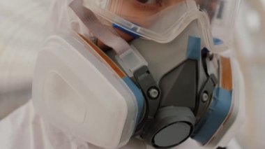 Koruyucu giysili, gözlüklü ve solunum cihazlı virüs bilimciyi kapatın.