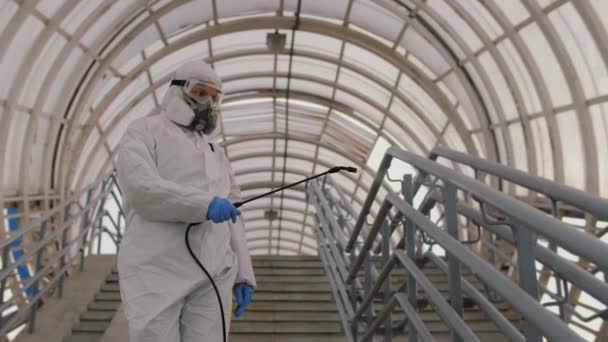 Epidemiologe in Schutzuniform desinfiziert Oberfläche im öffentlichen Raum — Stockvideo