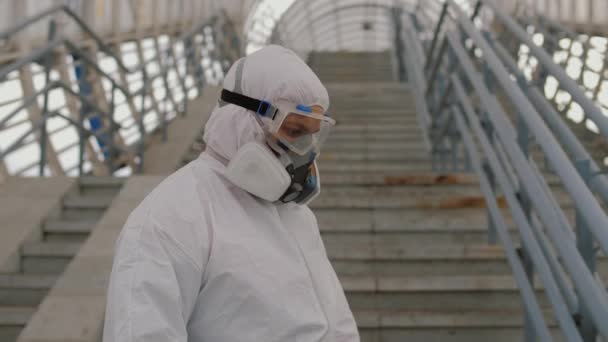 Virologe in Schutzuniform desinfiziert Oberfläche im öffentlichen Raum — Stockvideo