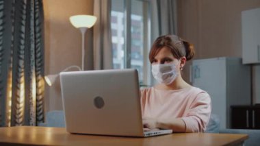 Tıbbi maske takan kadın evden uzakta çalışıyor, kendini izole ediyor.