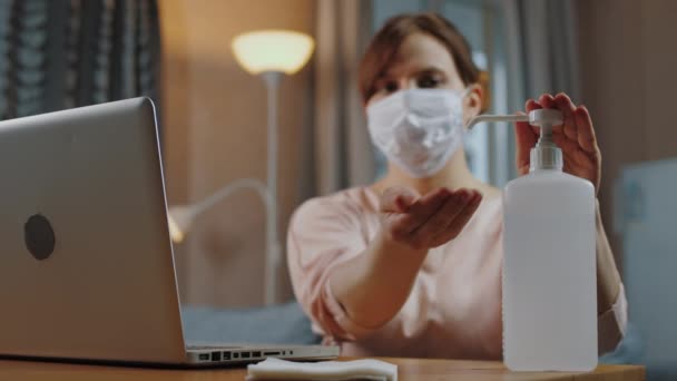 Женщина дезинфицирует руки антисептиком перед работой на ноутбуке — стоковое видео