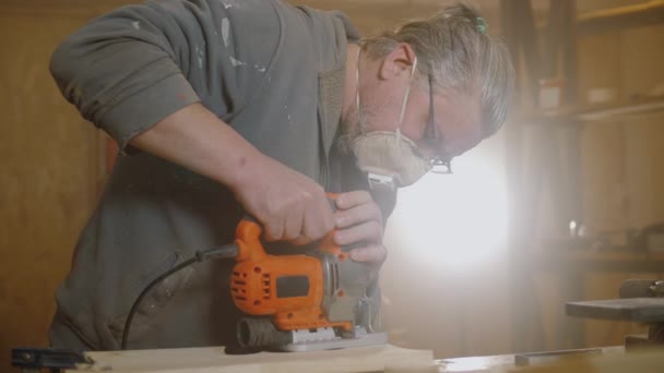 Carpintero utiliza rompecabezas eléctrico para cortar tablero de madera, artesano de madera trabajando — Vídeos de Stock