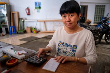 Asyalı Endonezyalı kadınlar, küçük yerel bir aile işletmesi sahibi, ya da yerel olarak Warung olarak adlandırılan, masasının kârını hesaplayan. Seçici Odaklanma.