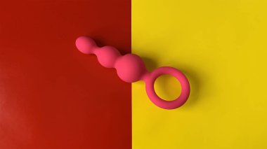 Pembe anal tıkaç. Seks oyuncağı, kıç tıkacı. Anal oyuncak. Kırmızı ve sarı arka plan. Seks dükkanı için kullanışlı. Düz yatay foto