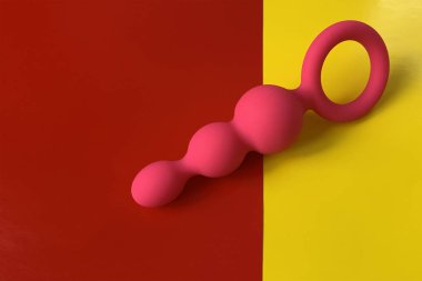 Seks oyuncağı. Kıç tıkacı. Pembe anal tıkaç. Anal oyuncak. Kırmızı ve sarı arka plan. Seks dükkanı için kullanışlı.