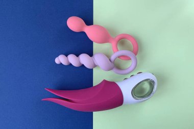 Vibratör ve iki kıç tıkacı. Seks oyuncakları. İki renk arkaplan. Seks dükkanı için kullanışlı.