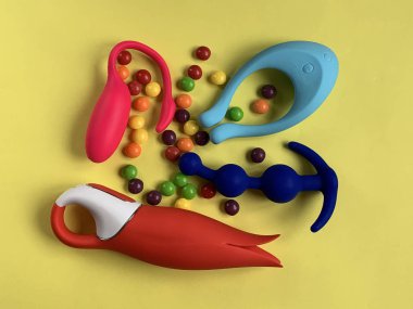 Dört seks oyuncağı. Sarı arka planda vibratörler ve anal tıkaçlar var. Seks dükkanı ya da yetişkinler için kullanışlı