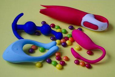 Dört seks oyuncağı. Sarı arka planda vibratörler ve anal tıkaçlar var. Seks dükkanı için kullanışlı