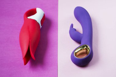 Vibratörler. Pembe arka planda titreşimli iki seks oyuncağı. Seks için titreşimli dildolar. Yetişkinler için kullanışlı, seks dükkanı. Kapat.