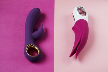 Vibratörler. Titreşimli pembe ve mor dildolar. Renkli arka plandaki kadınlar için seks oyuncakları. Yetişkin için kullanışlı