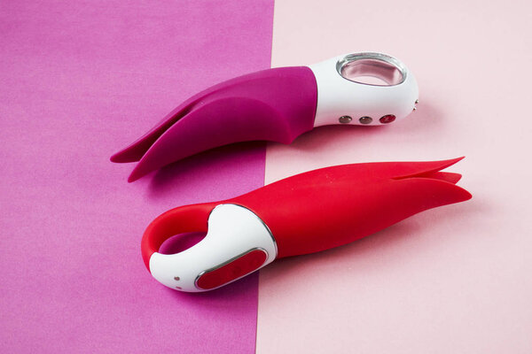 Vibrators. Pink and red dildos with vibration. Sex toys for women on color background. Useful for adult