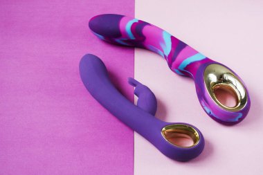 Vibratörler. Pembe arka planda titreşimli iki seks oyuncağı. Seks için titreşimli dildolar. Seks dükkanı için kullanışlı