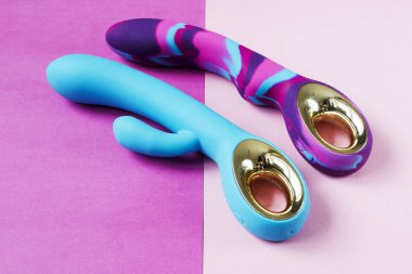 Vibratörler. Pembe arka planda titreşimli iki seks oyuncağı. Seks için titreşimli dildolar. Yetişkinler için kullanışlı, seks dükkanı