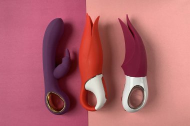 Seks için vibratörler. Pembe arka planda titreşimi olan üç vajinal dildo. Seks oyuncakları. Yetişkinler için kullanışlı, seks dükkanı.