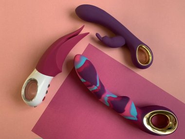 Seks için vibratörler. Renkli arka planda üç kadın için seks oyuncağı. Yetişkin için kullanışlı