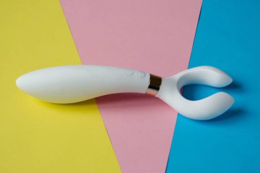 Seks oyuncağı. Renkli arka planda beyaz vibratör. Yetişkin için kullanışlı