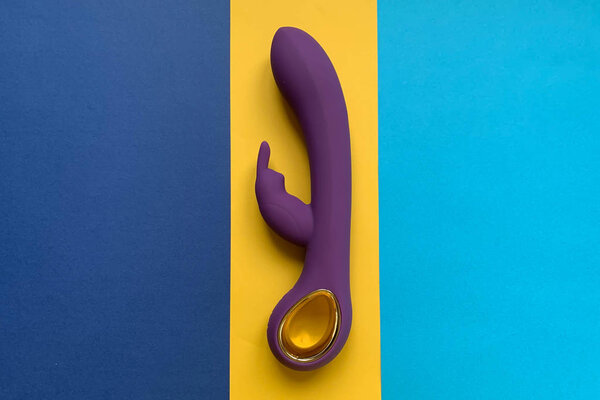 Sex toy. Vibrator on a blue-yellow background. Useful for adult