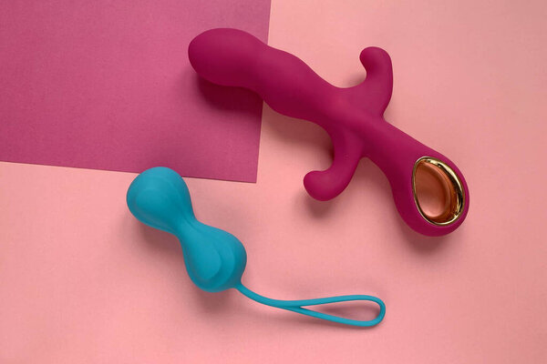 Sex toys. Pink vibrator ang blue  jiggle balls on a pink background. Sex gadget and masturbation device