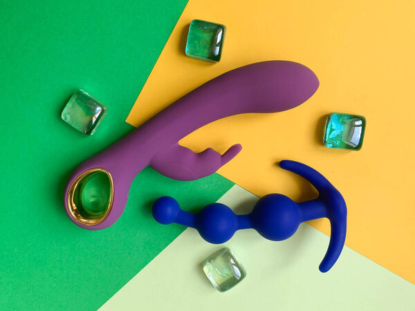 Sex toys. Purple vibrator and blue butt plug on a green-yellow background. Useful for sex shop, adult