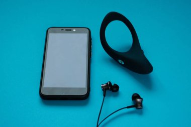 Seks oyuncağı. Mavi arka planda beyaz titreşimli sik yüzüğü ve telefon. Yetişkin için kullanışlı
