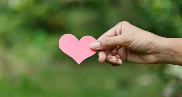 Manos sosteniendo el corazón contra la naturaleza — Foto de Stock