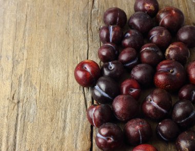 Bir grup kırmızı erik meyvesi, ahşap arka deliğin üzerinde uzanıyordu.