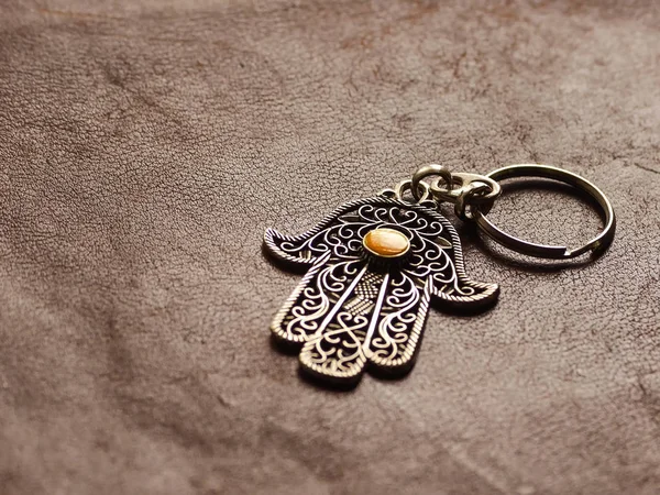 Prsten na klíče v podobě Fatimy Hand na hnědém koženém pozadí. Starověký symbol a tradiční moderní turistický suvenýr Tuniska — Stock fotografie