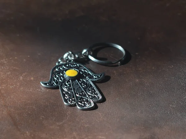 Schlüsselanhänger in Form einer Fatima-Hand auf braunem Lederhintergrund. antikes Symbol und traditionelles modernes touristisches Souvenir von Thunfisch — Stockfoto