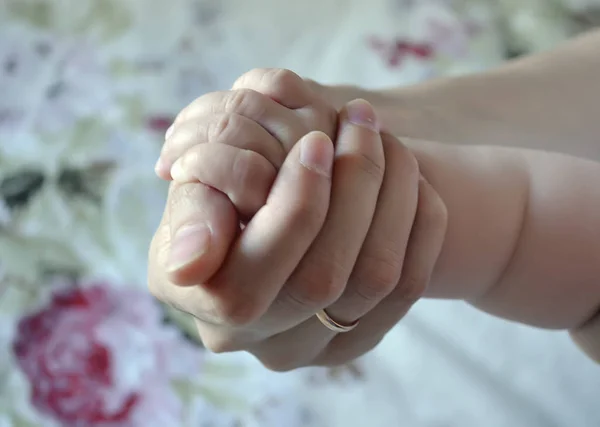 Petit bras de bébé dans une main féminine. Thème de la maternité et de l'enfance, protection de l'enfance . — Photo
