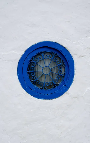 白い壁に模様のグリルのある青いフレームの丸窓 — ストック写真