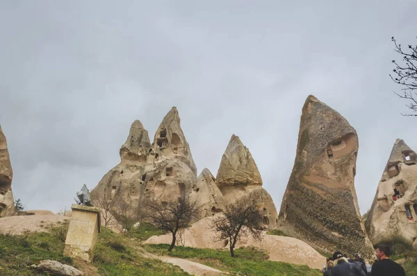 Dwellings in the rocks of volcanic tuff in Cappadocia. A group of tourists visiting the sights of the National Park of Goreme — Stock Photo, Image