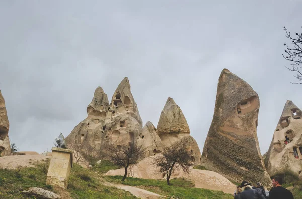 Viviendas en las rocas de toba volcánica en Capadocia. Un grupo de turistas que visitan los lugares de interés del Parque Nacional de Goreme — Foto de Stock