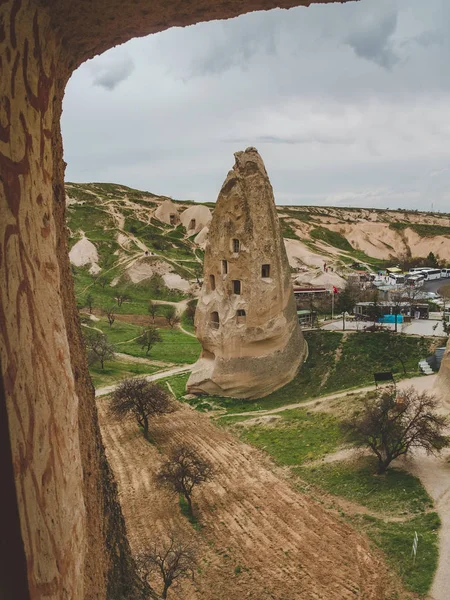 Dwellings in the rocks of volcanic tuff in Turkish Cappadocia view through stone arch. Goreme National Park. — Stock Photo, Image