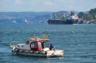 İstanbul, Türkiye, 21 Eylül 2018. Büyük bir kargo gemisi, ön planda bir balıkçıyla birlikte küçük bir balıkçı teknesi olan Boğaz boyunca gider.