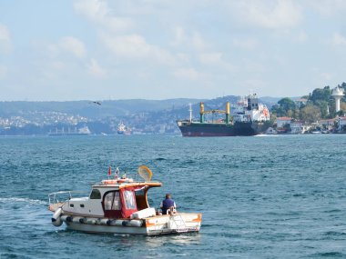 İstanbul, Türkiye, 21 Eylül 2018. Büyük bir kargo gemisi, ön planda bir balıkçıyla birlikte küçük bir balıkçı teknesi olan Boğaz boyunca gider.