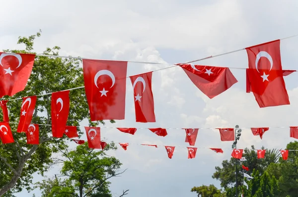 Bandeiras turcas na praça no centro de Antalya contra de céu nublado e árvores . — Fotografia de Stock