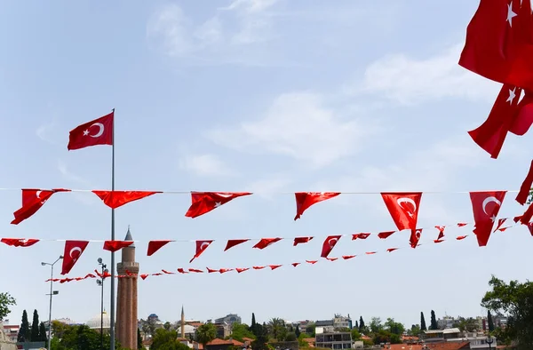 Bandeiras turcas na praça no centro de Antalya, mesquita minare Yivli no fundo — Fotografia de Stock