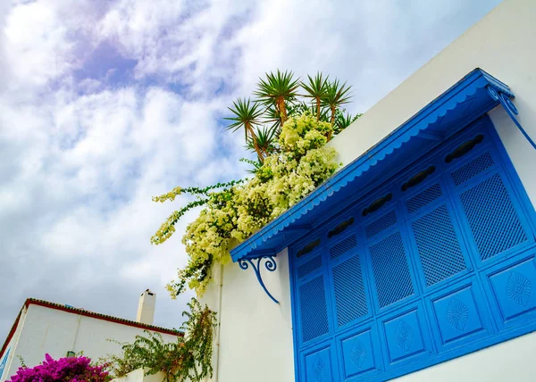 Persianas de listones azules en el estilo mediterráneo contra el cielo y las flores —  Fotos de Stock