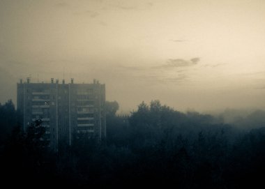 Şehrin varoşlarındaki çok katlı panelli ev, ürkütücü sis manzarası. Taneli bir çekim için stil.