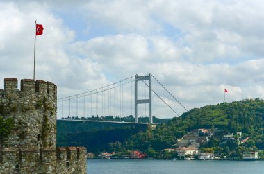 Rumeli Hisar şatosundan İstanbul 'un İstanbul ve İstanbul' un Asya kesimindeki Boğaz Köprüsü 'ne görüntü. Kulede ve diğer tarafta Türk bayrakları