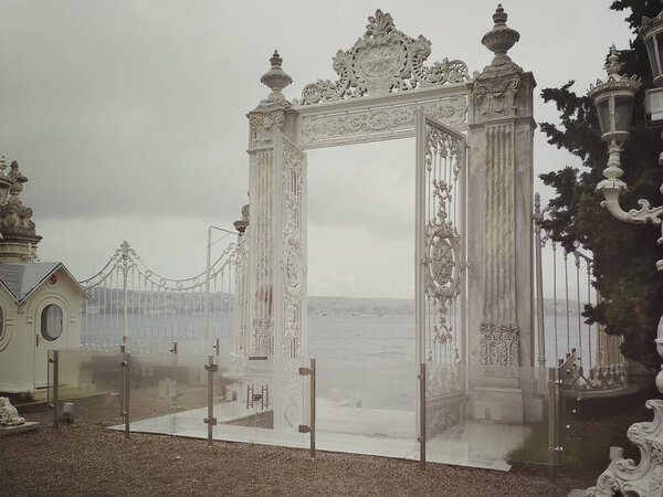Стамбул, Турция - 25 сентября 2018 года. Декоративные белые мраморные ворота дворца Долмабахче на берегу Босфора в пасмурный день
