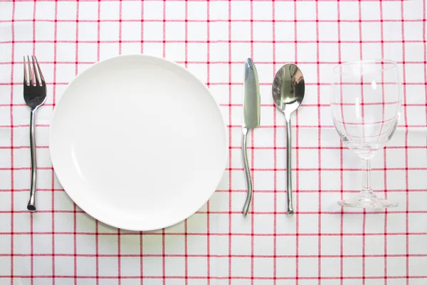 Cuchillo plato blanco y cuchara tenedor sobre mantel rojo a cuadros — Foto de Stock