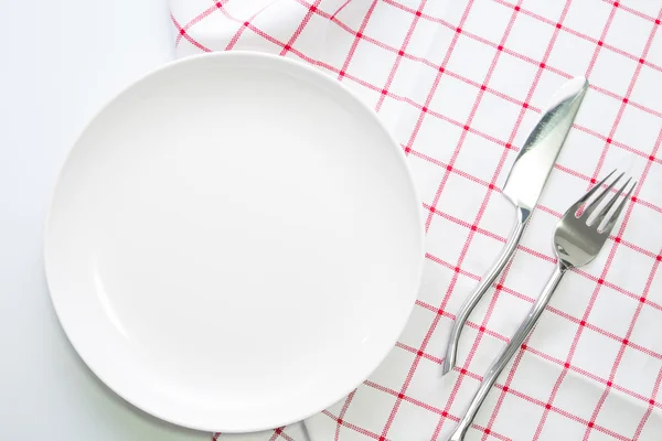 Empty white plate and fork knife on red checked tablecloth — Stock fotografie