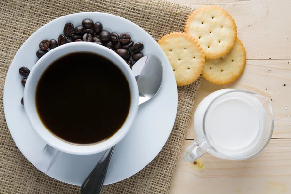 Xícara de café e leite com biscoito na mesa de madeira — Fotografia de Stock