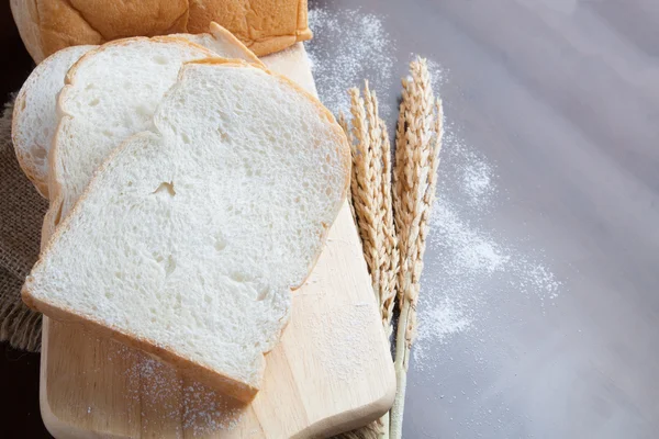 Pão com espigas de trigo na placa escura com farinha — Fotografia de Stock